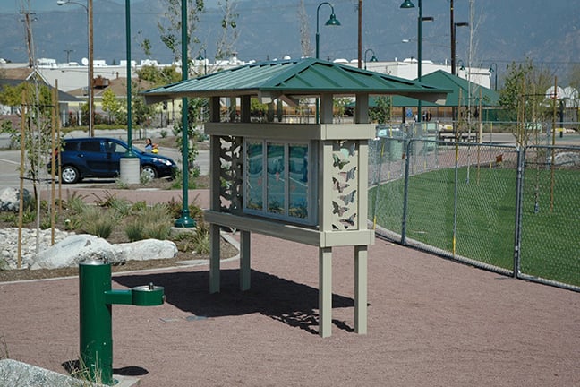 Transit hip shelter with green roof in park with fenced in field in the background. 